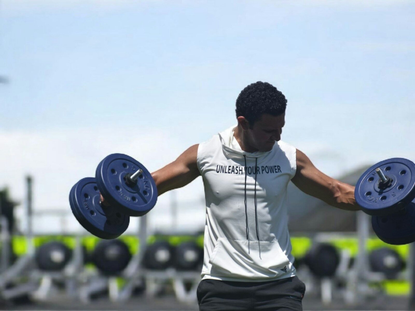 Man lifting dumbbells at outdoor gym.